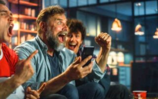 How to make money off bonus bets: Three excited men celebrating a winning bet while watching a game, capturing the thrill and potential rewards of sports betting.