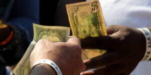 A close-up of hands exchanging money, representing the financial transactions involved in betting.