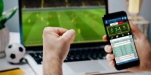 Man celebrates winning a football bet while watching live match on laptop.