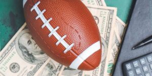 AFL betting concept showing an American football placed on US dollar bills beside a notebook, pen, and calculator