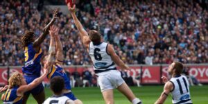 AFL players leap into the air contesting a mark during a high-stakes match in front of a packed stadium