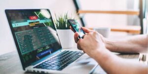Man using AI betting bots on mobile and laptop during live sports betting 