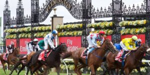 Thoroughbred racehorses break from the gates at Flemington Racecourse with jockeys in colourful silks during a major horse racing event 