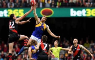Players from two Australian Football League teams contest a high ball during a match, with a visible bet365 banner in the background, symbolising the excitement of those who bet on AFL games.