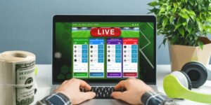 Person placing live sports bets on a laptop with betting markets displayed on the screen.