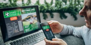 Man checking live sports betting markets on a phone and laptop, similar to platforms offered by Australian bookmakers.