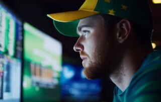 Man analysing live betting data on multiple screens for Dutching strategy